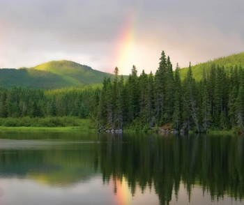 Lake, forest, mountains with sun through haze
